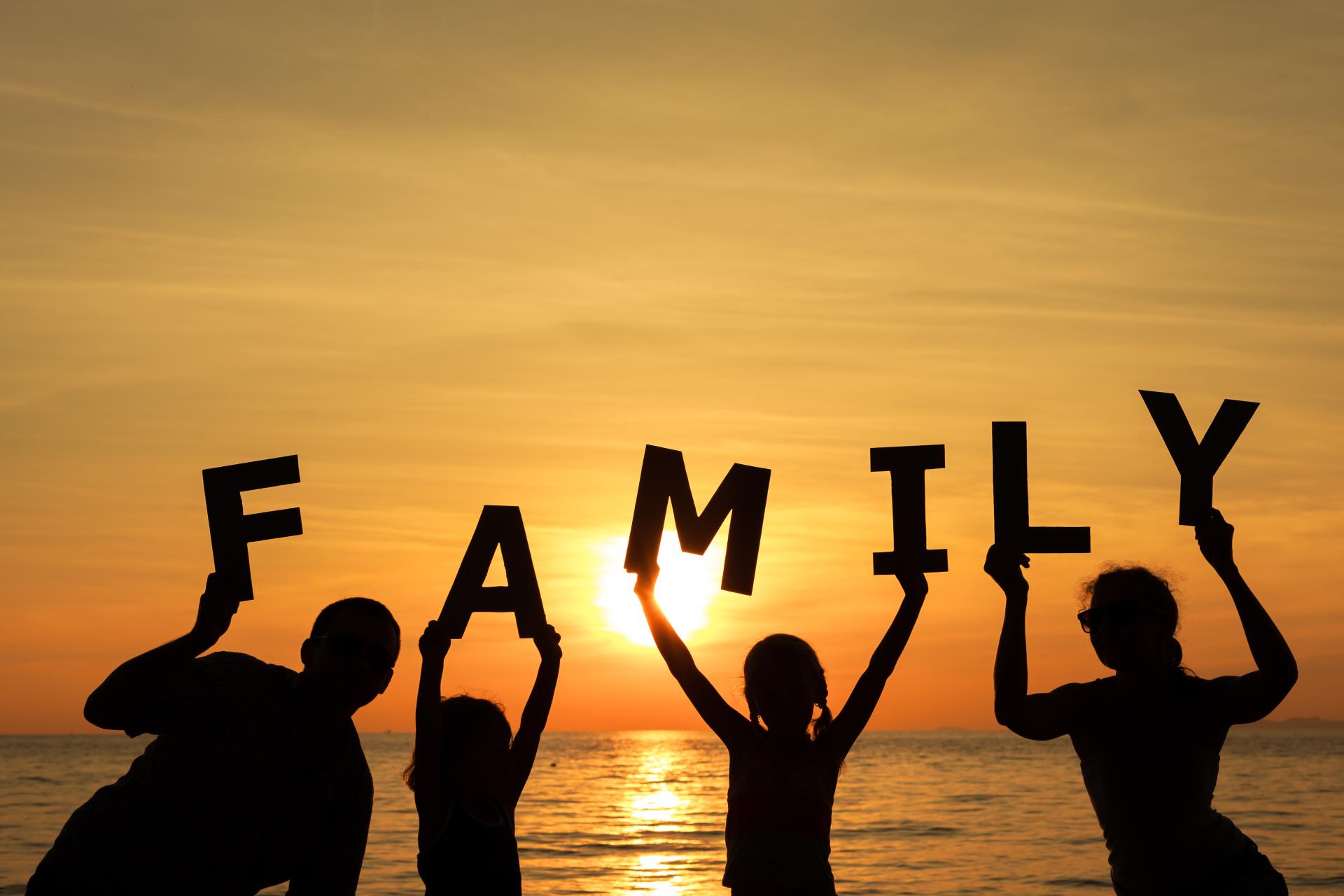 Family Holding Word Family with Sunset Beach Scene Background