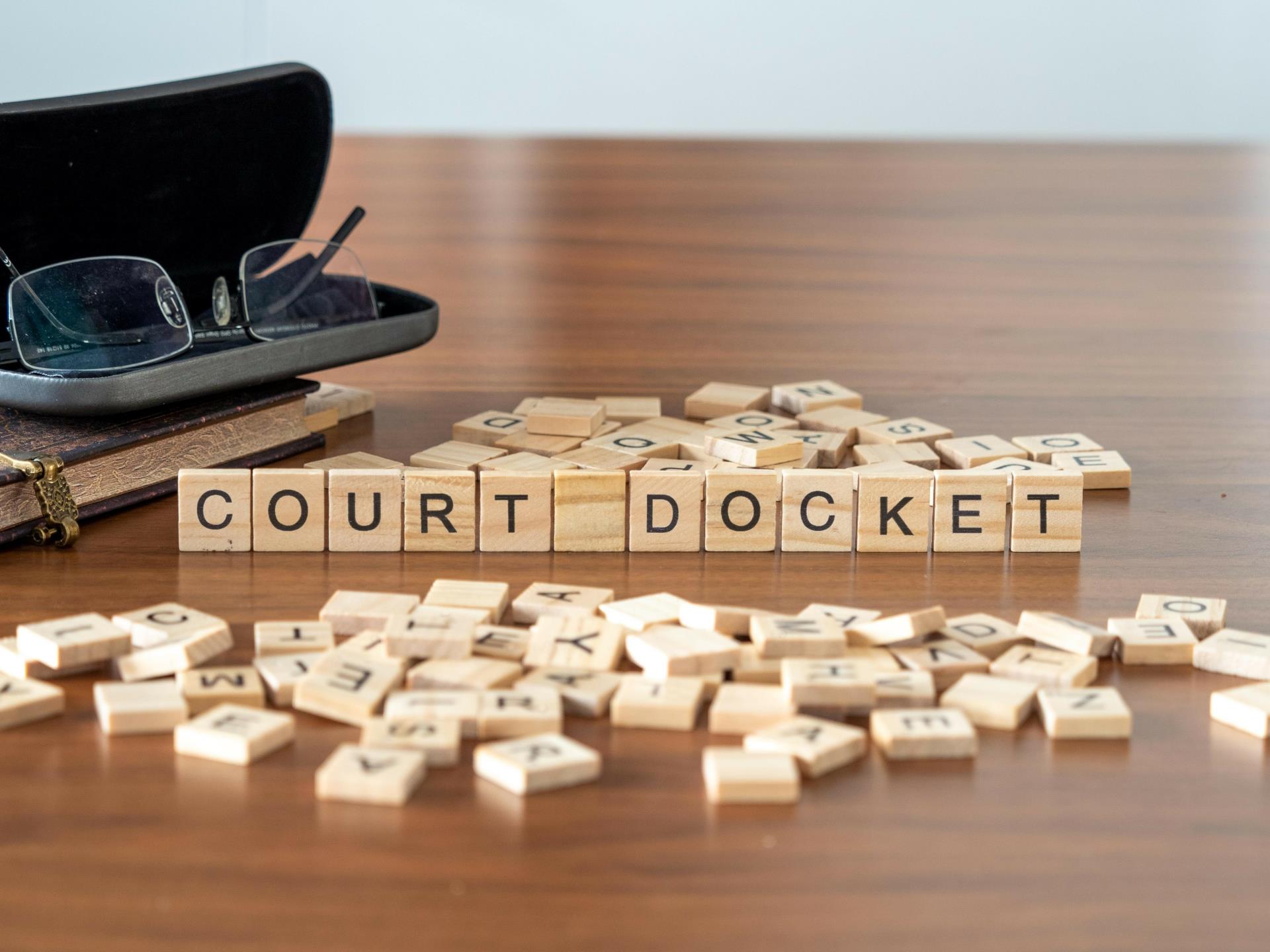 court docket word or concept represented by wooden letter tiles on a wooden table with glasses and a book