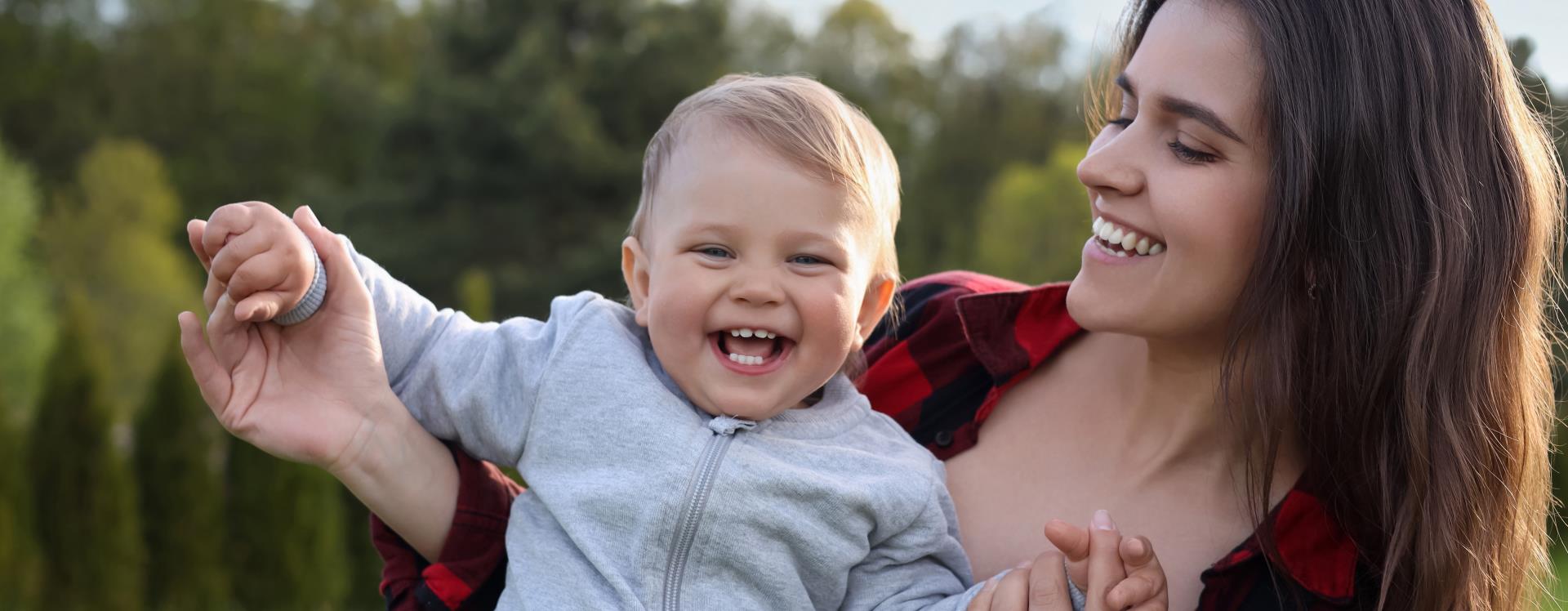 Happy mother with baby in park on sunny day.